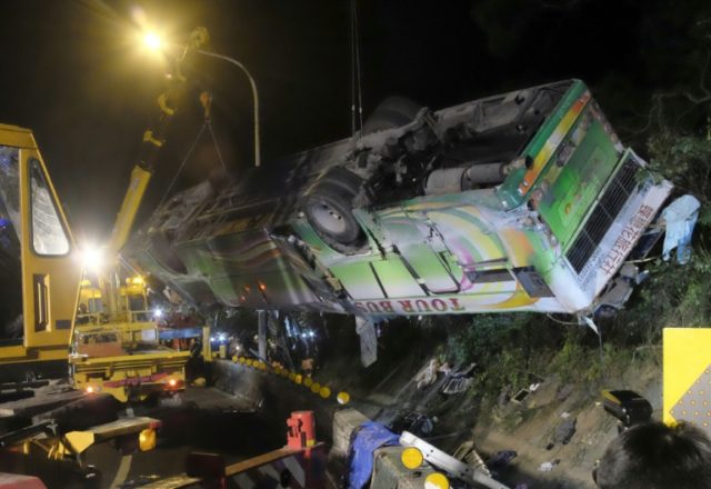 A bus that crashed along a highway is lifted by cranes in Taipei on February 14, 2017