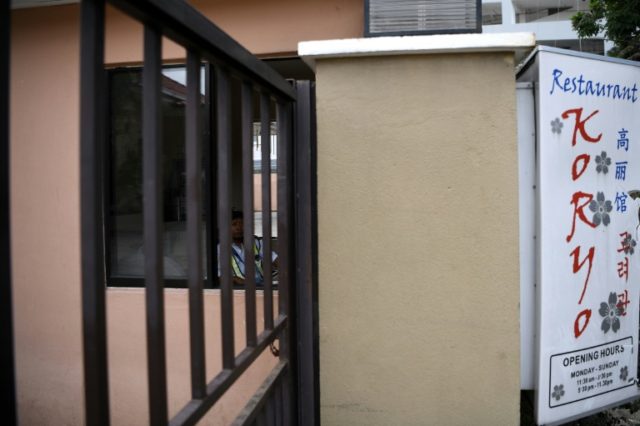 A private security guard sits inside the closed premises of the Pyongyang Koryo Restaurant