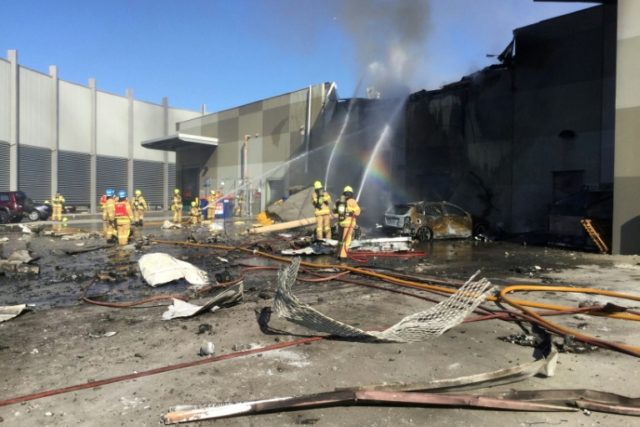 Firemen put out a blaze from a light aircraft which exploded as it smashed into a shopping