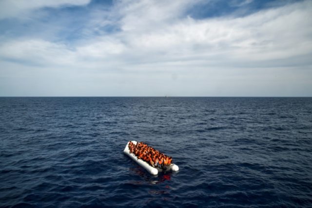 Migrants and refugees on a rubber boat wait off the coast of Libya to be evacuated during