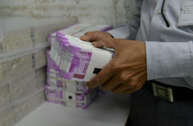 An Indian bank employee checks stacks of new 2,000 rupee notes