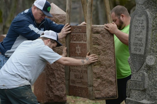 Volunteers from a local monument company help to reset vandalized headstones at Chesed She
