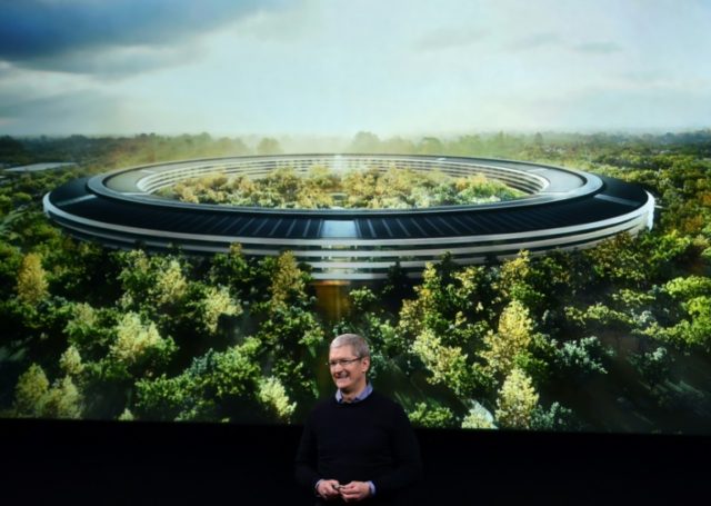 Apple CEO Tim Cook stands in front of a slide of the company's new campus which is under c