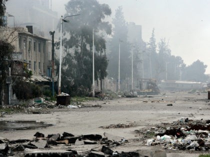 In this photo released by the Syrian official news agency SANA, damaged and blocked street