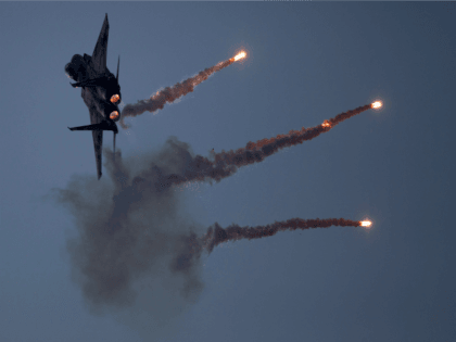 An Israeli Air Force fighter jet releases flares during an acrobatics display during a gra