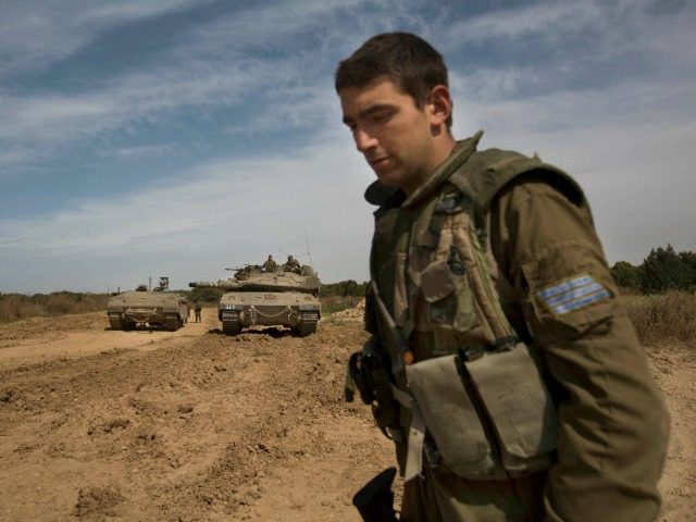 Israeli soldier walks by a tank near the Israel Gaza border, Wednesday, May 4, 2016. Israe