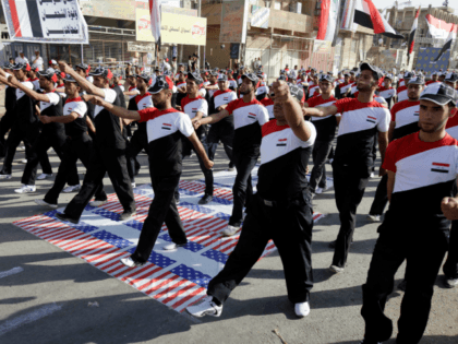In this Thursday, May 26, 2011 file photo, militiamen loyal to cleric Muqtada al-Sadr march over the American flag while wearing shirts bearing the Iraqi flag in the Sadr City district of Baghdad, Iraq. Shiite militias backed by Iran have ramped up attacks on U.S. troops in Iraq, making June …
