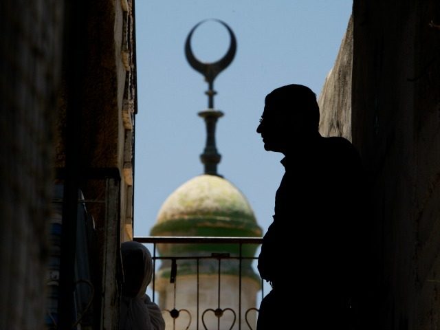 Backdropped by a mosque minaret Palestinians watch the funeral of Mohammed Al Amma, 17, in