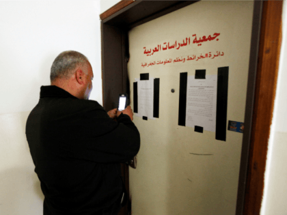 A man takes a photo of the sealed offices of Khalil Tufagji, a prominent Palestinian carto