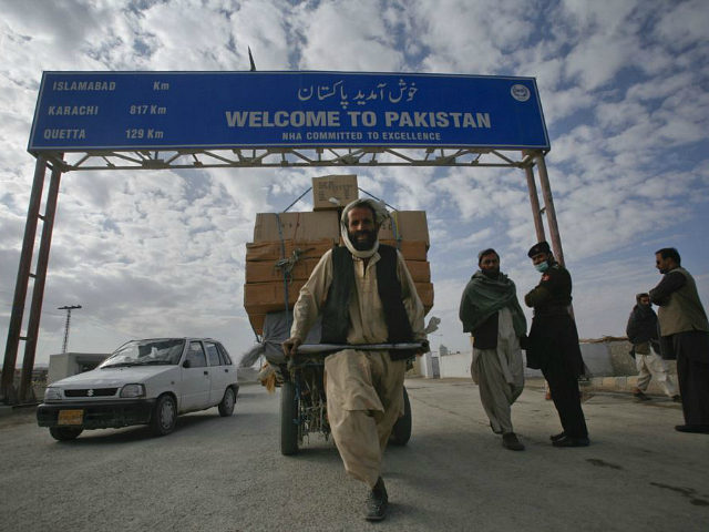A Pashtun man passes a road sign while pulling supplies towards the Pakistan-Afghanistan b