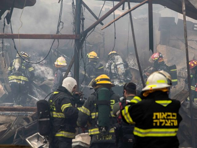 Israeli firefighters and rescue workers inspect the rubble after a fire ripped through a f