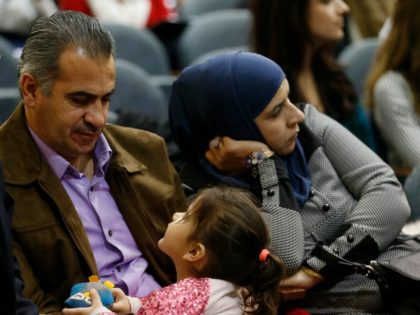 Syrian refugee Morad Alteibawi, left, talks to his 4-year-old daughter, Roma, as his wife