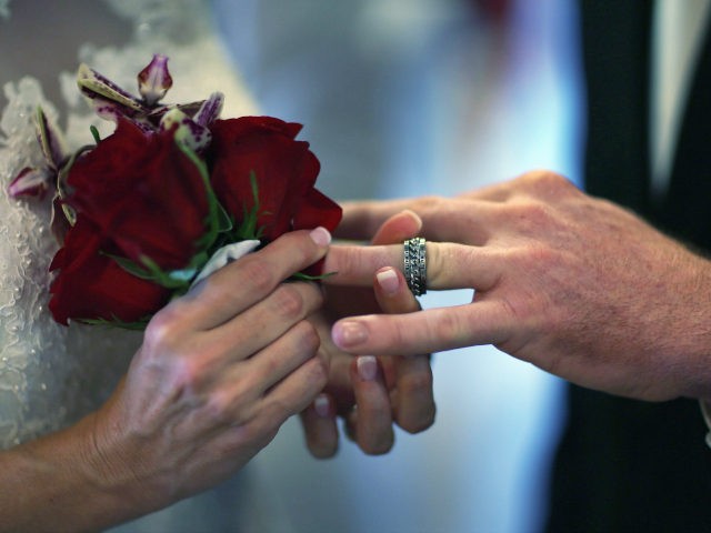 WEST PALM BEACH, FL - FEBRUARY 14: Luanne Round slips a ring on the finger of her husband,