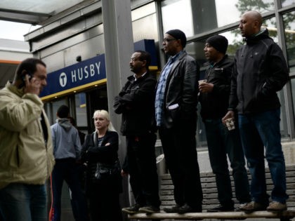 People stand on a street bench next to Husby subway station as they attend a demonstration against police violence and vandalism in the Stockholm suburb of Husby on May 22, 2013. Rioting spread across Stockholm immigrant districts in a third night of unrest, raising fears that decades of integration efforts …