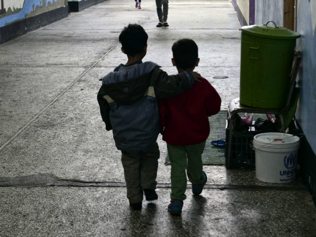 TOPSHOT - Children walk through a former industrial warehouse at the Oinofyta refugee camp