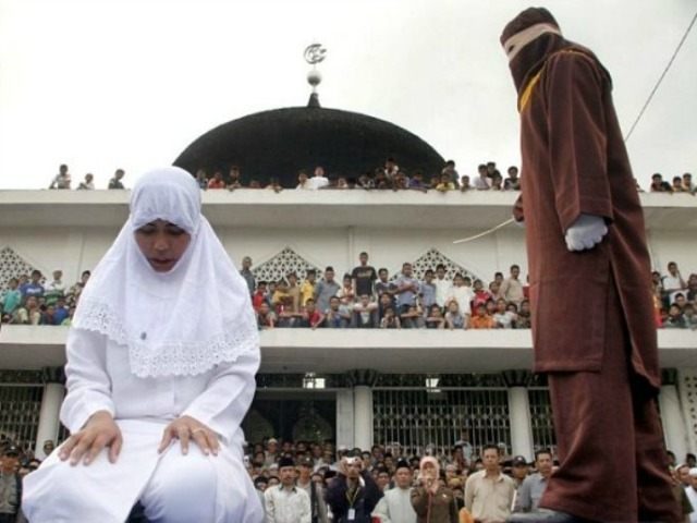 An officer canes a woman who violated strict Syariah laws