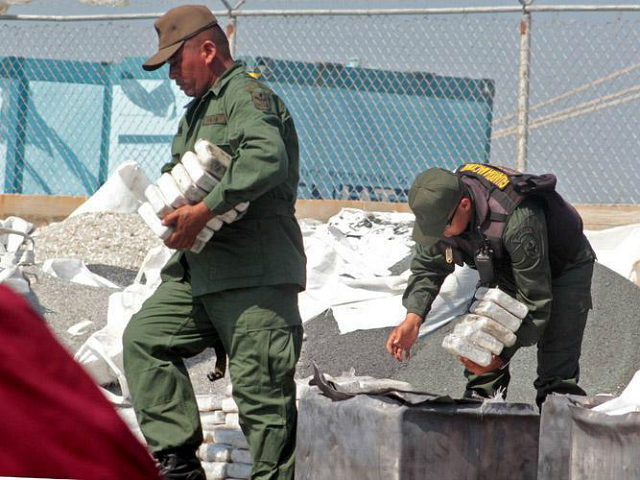 A member of the National Guard looks after 2.6 tons of cocaine seized in Maracaibo, Zulia state, northwest of Venezuela, on April 25, 2013. According to the minister of Interior and Justice, Miguel Rodriguez, the drug was to be sent to Honduras. AFP PHOTO/Jimmy Pirela (Photo credit should read JIMMY …