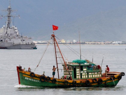 A Vietnamese fishing boat goes past the USS Chung-Hoon warship (rear) at Tien Sa port, in Vietnam's central Danang city, July 15, 2011. REUTERS/Kham