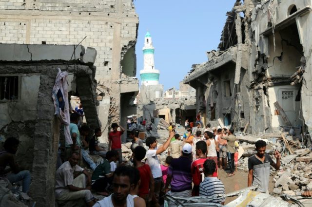 Residents gather amidst the rubble of buildings destroyed during Saudi-led air strikes in