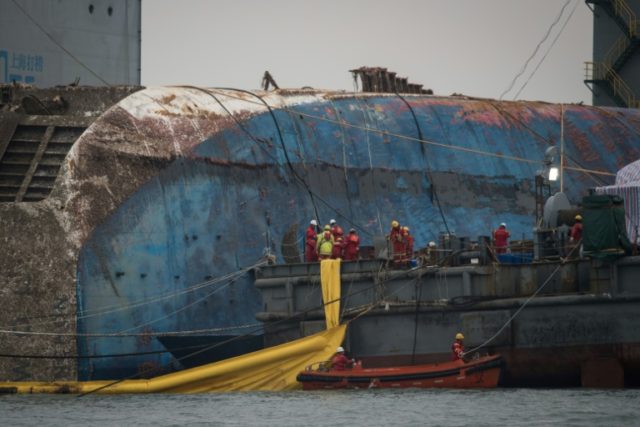 Workers aboard a Chinese salvage vessel participate in the salvage operation of the Sewol