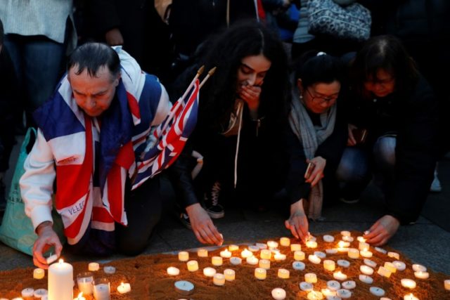 People in London light candles in tribute to the victims of the attack outside the British