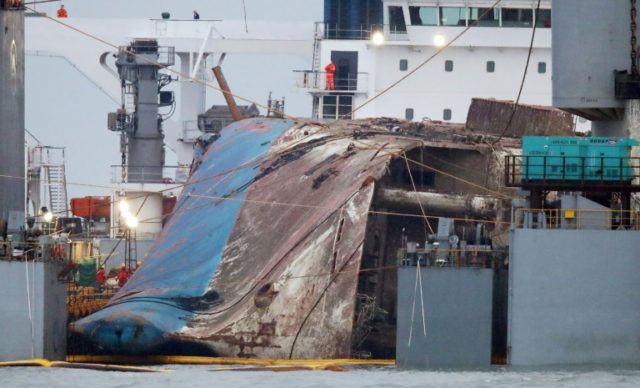South Korea's sunken Sewol ferry is hauled onto a giant heavy lifting ship ready to be tow