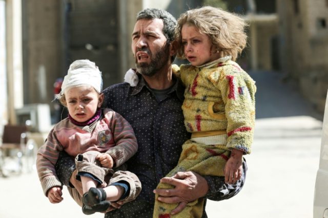 A Syrian man carries two injured children after a reported air strike in the rebel-control