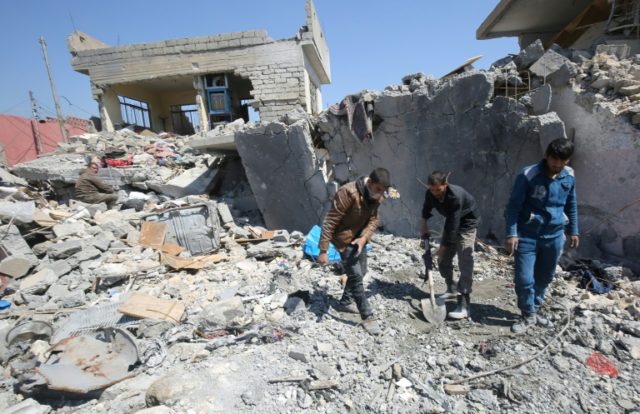 Iraqis clean up the rubble of destroyed buildings in the Mosul al-Jadida area following ai