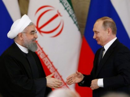 Russian President Vladimir Putin (R) shakes hands with his Iranian counterpart Hassan Rouh