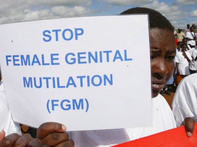 A Masai girl holds a protest sign during the anti-Female Genital Mutilation (FGM) run in Kilgoris, Kenya, April 21, 2007. At least 2 million girls every year are at a risk of undergoing FGM. The cut, which is generally done without anesthesia may have lifelong health consequences. (AP Photo/Sayyid Azim)