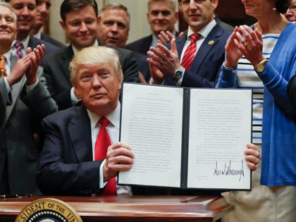 President Donald Trump holds up a signed Executive Order in the Roosevelt Room of the White House in Washington, Friday, April 28, 2017, directing the Interior Department to begin review of restrictive drilling policies for the outer-continental shelf. (AP Photo/Pablo Martinez)
