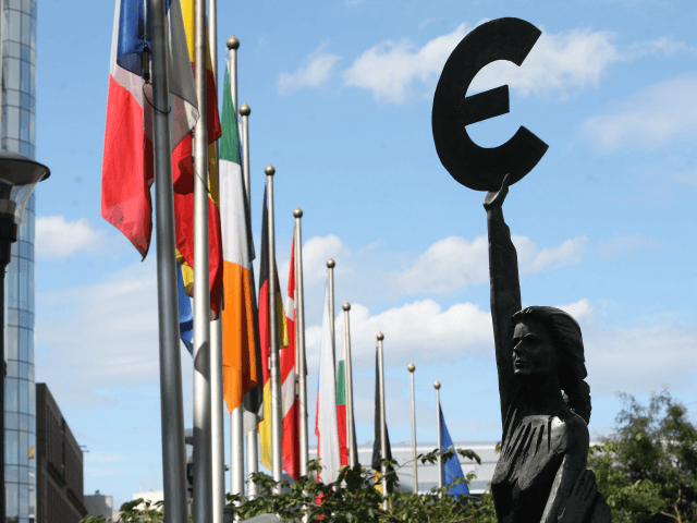 A statue holding the symbol of the Euro, the European common currency, stands in front of the European Parliament building on August 16 and 2011 in Brussels, Belgium.