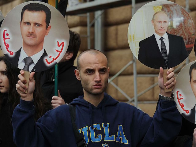 A man holds portrait of Russia's President Vladimir Putin (R) and Syria's Presi