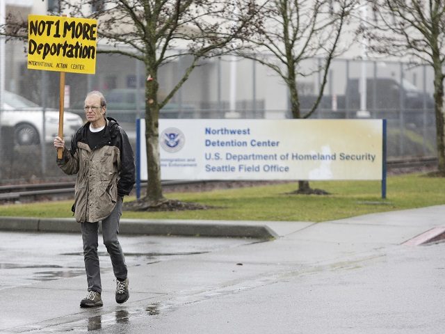 A protester walks past the entrance of the Northwest Detention Center as people attend th