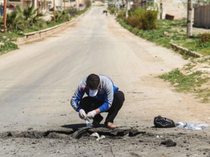 A Syrian man collects samples from the site of a suspected toxic gas attack in Khan Sheikh