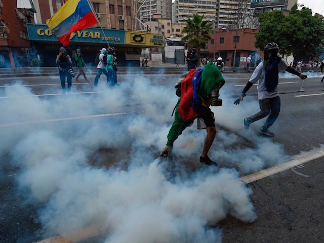 A demonstrator pick up a tear gas canister thrown by the police during a rally against Venezuelan President Nicolas Maduro, in Caracas on April 19, 2017. Venezuela braced for rival demonstrations Wednesday for and against President Nicolas Maduro, whose push to tighten his grip on power has triggered waves of …