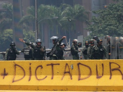 A Venezuelan Bolivarian National Guard officer throws a tear gas grenade towards demonstra