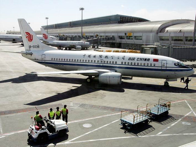 Chinese workers stand in front of an Air China Boeing B737 aircraft at Beijing Airport Mar