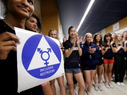 Deena Kennedy, left, holds a sticker for a new gender neutral bathroom as members of the c