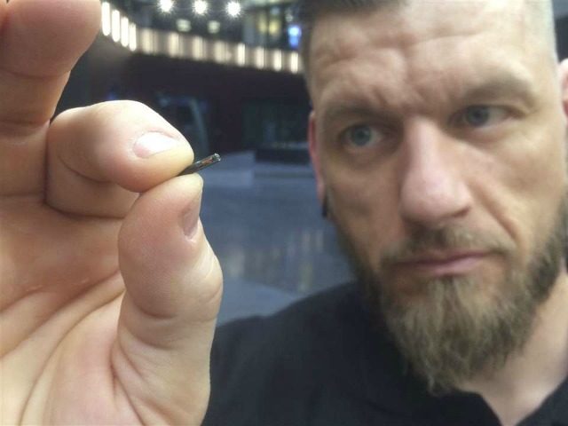 Self-described “body hacker” Jowan Osterlund from Biohax Sweden, holds a small microchip implant, similar to those implanted into workers at the Epicenter digital innovation business centre during a party at the co-working space in central Stockholm, Tuesday March 14, 2017. Microchips are being implanted into volunteers to help them open …