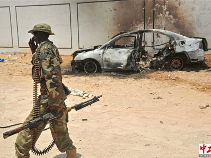 A Somali soldier patrols next to the burnt-out wreckage of a car that was used by suspected al-shabab fighters on April 16, 2017. Somali security forces shot dead two suspected al-shabab militants, an Al-Qaeda linked extremist group, who were said to be involved in firing rockets. / AFP PHOTO / …