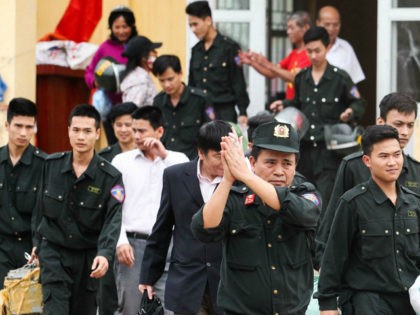 Released policemen (wearing dark uniforms) walk out from the communal house at Dong Tam commune, My Duc district in Hanoi on April 22, 2017. More than a dozen police and officials held hostage by Vietnamese villagers over a land dispute were released on April 22, state media reported, ending a …