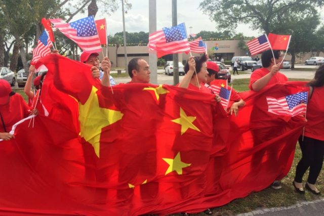 A group of China supporters wave Chinese and US flags as they wait for the arrival of Chin