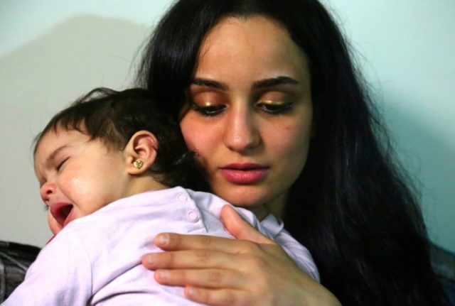 Twenty-three year old Islam Maytat from Morocco comforts one of her two children, Maria, d