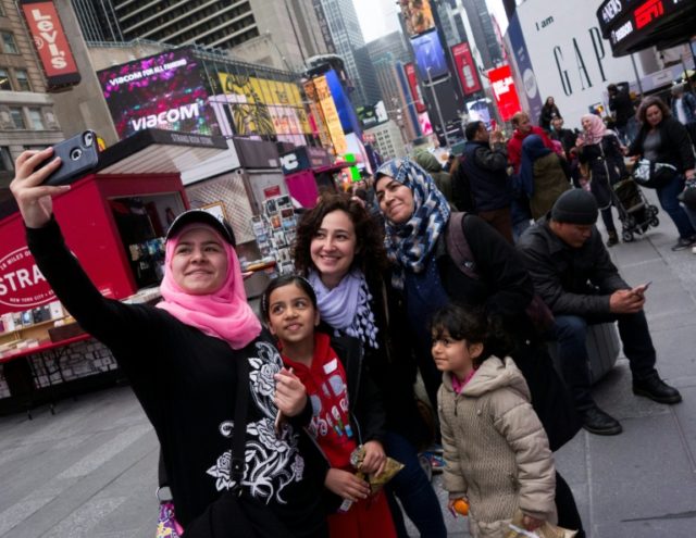 Syrian and Iraqi refugee families take selfies in Times Square during a tour of Manhattan