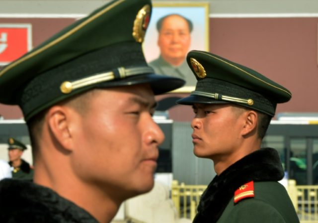 Chinese paramilitary police stand guard in front of the portrait of late leader Mao Zedong