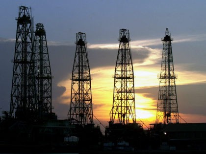 FILE - In this Aug. 1, 2004 file photo, the sun sets behind an oil drilling rig near Cabim