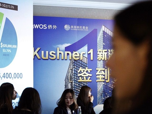 Chinese staff wait for investors at a reception desk during an event promoting EB-5 invest