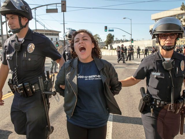 High school student Claudia Rueda, 17, center, is arrested by Los Angeles Police officers for failing to disperse, as protestors blocked the intersection of the Los Angeles Sheriff's Department Twin Tower Correctional Facility in Los Angeles Thursday, Sept. 6, 2012.