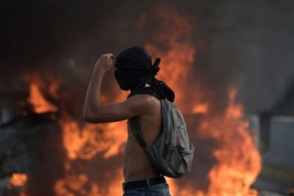 CARACAS, VENEZUELA - APRIL 24: Venezuelan opposition activist cover his face in front of b